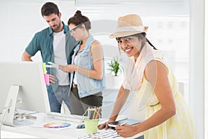 Smiling designer in front of colleagues using colour wheel