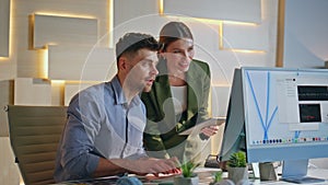 Smiling designers working computer in agency. Woman team leader helping man