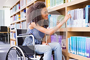 Smiling disabled student in library picking book photo