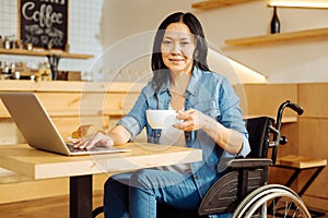 Smiling disabled woman drinking coffee