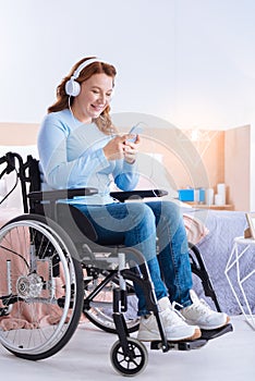 Smiling disabled woman wearing headset and using her phone