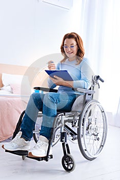 Smiling disabled woman writing on a sheet of paper