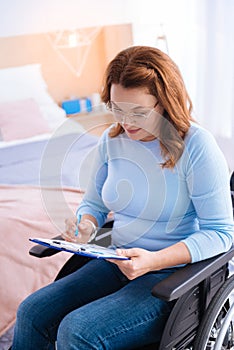 Smiling disabled woman writing and wearing glasses