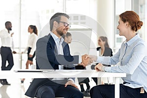 Smiling diverse business partners handshake closing deal at meeting