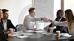 Smiling diverse business partners handshake greeting at meeting