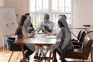 Smiling diverse colleagues brainstorm laugh at office meeting