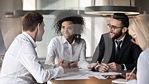 Smiling diverse colleagues discuss business ideas at team briefing