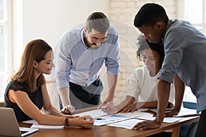 Smiling diverse colleagues discuss paperwork at meeting