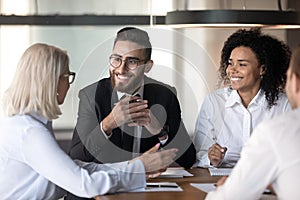 Smiling diverse colleagues discussing ideas at office briefing