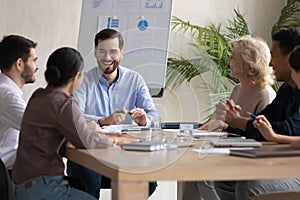 Smiling diverse colleagues laugh brainstorming in office