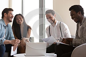 Smiling diverse colleagues laugh cooperating at briefing in office