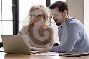 Smiling diverse colleagues work on laptop at meeting