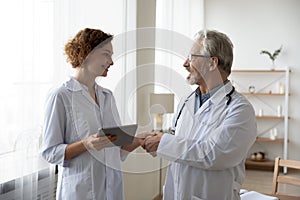 Smiling diverse doctors handshake greeting in hospital