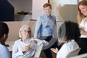 Smiling diverse employees brainstorm sharing ideas at workplace