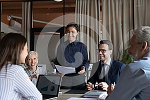 Smiling diverse employees discuss ideas at team meeting