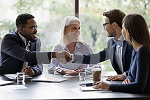 Smiling diverse employees handshake at briefing in office