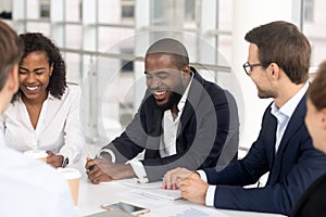 Smiling diverse employees laugh brainstorming at office meeting