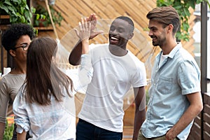 Smiling diverse friends give high five greeting at meeting