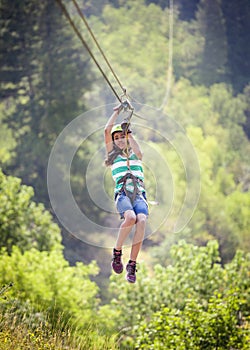 Smiling diverse girl riding a zipline through the forest