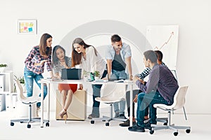 Smiling diverse group of young people working and communicating together in office