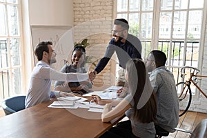 Smiling diverse male colleagues handshake at business briefing