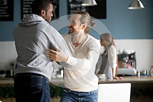 Smiling diverse male friends embracing greeting at meeting in ca