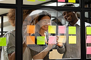 Smiling multiracial colleagues develop project on sticky notes photo