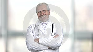 Smiling doctor crossed arms on blurred background.