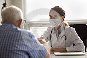 Smiling doctor in facemask handshake mature male patient