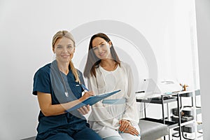 Smiling doctor fills out the medical report form on medical care of patients during appointment