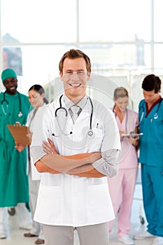 Smiling doctor with his team in the background