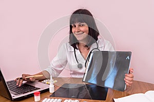 Smiling doctor with laptop showing patient`s x-ray