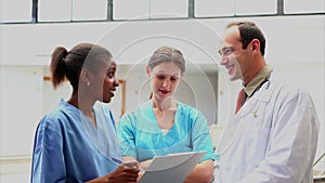 Smiling doctor listening to a nurse holding a clipboard