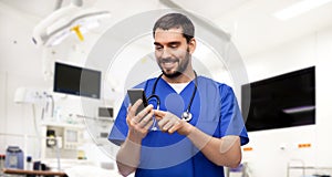 smiling doctor or male nurse using smartphone