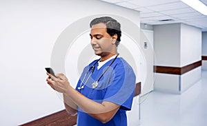 smiling doctor or male nurse using smartphone