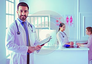 Smiling doctor man standing in front of his team and patient