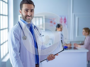 Smiling doctor man standing in front of his team and patient