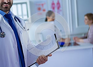 Smiling doctor man standing in front of his team and patient