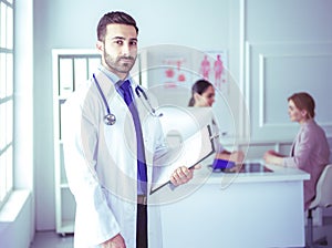 Smiling doctor man standing in front of his team and patient