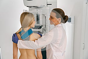 Smiling doctor prepairing woman before doing mammogram x-ray to check for breast cancer at hospital