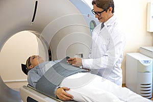 Smiling doctor putting immobilizing belt on patient before CT scan