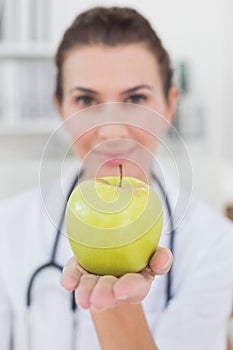 Smiling doctor showing apple