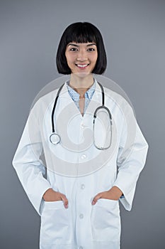Doctor standing with hands in pocket against white background
