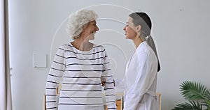 Smiling doctor supporting middle aged patient with walking frame.