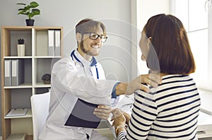 Smiling doctor talking to woman, touching her shoulder, supporting and reassuring her