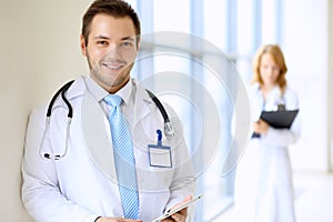 Smiling doctor waiting for his team while standing upright