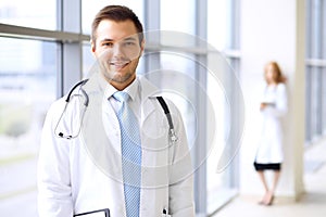 Smiling doctor waiting for his team while standing upright