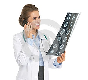 Smiling doctor woman with fluorography talking cell phone photo