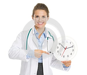Smiling doctor woman pointing on clock