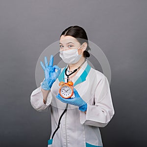 Smiling doctor woman pointing on clock, time to vaccine